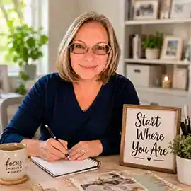 vicki-robinson-begin-anywhere.2b Vicki Robinson writing at a creative desk beside a framed Start Where You Are sign.